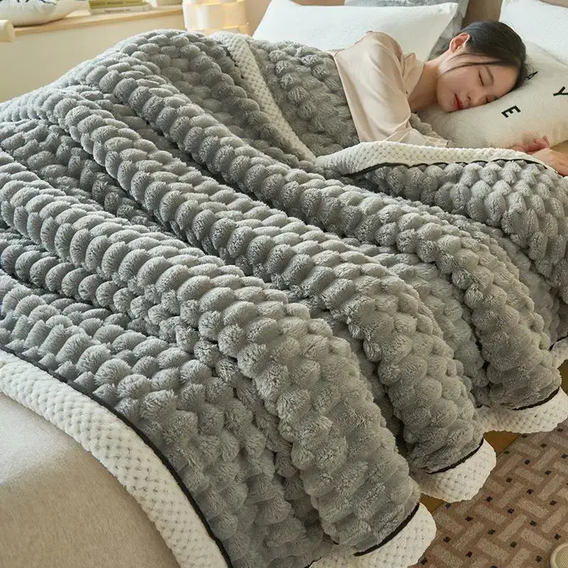 A cozy gray plush coral fleece bed blanket with honeycomb textured pom-poms and white trim for decorbites cozy coral