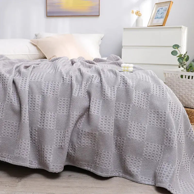 A soft light gray honeycomb waffle cotton throw blanket with textured diamond pattern draped over a bed decorbites honeycomb waffle