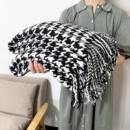 Black and white houndstooth patterned throw blanket with fringed edges.