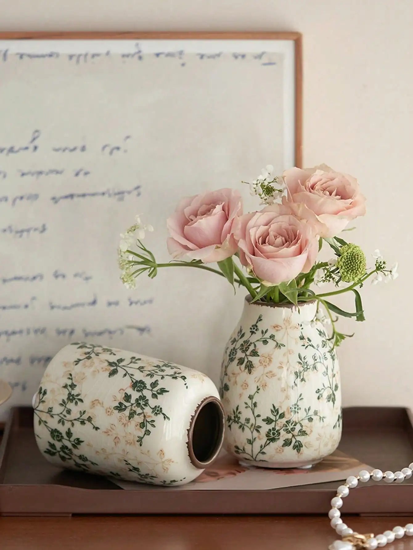 White ceramic crackle vase with green floral pattern holding pink roses for home decoration and flower display