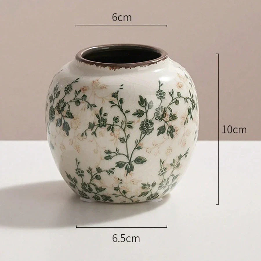 A round off-white handmade crackle vase with green floral patterns and dark brown rim for fresh or dry flower display