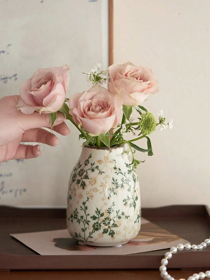 A cream-colored crackle vase with green floral pattern holding pink roses for home or office decoration