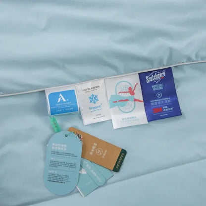 A light blue ice silk cooling blanket with multiple care tags including scotchgard moisture wicking by decorbites