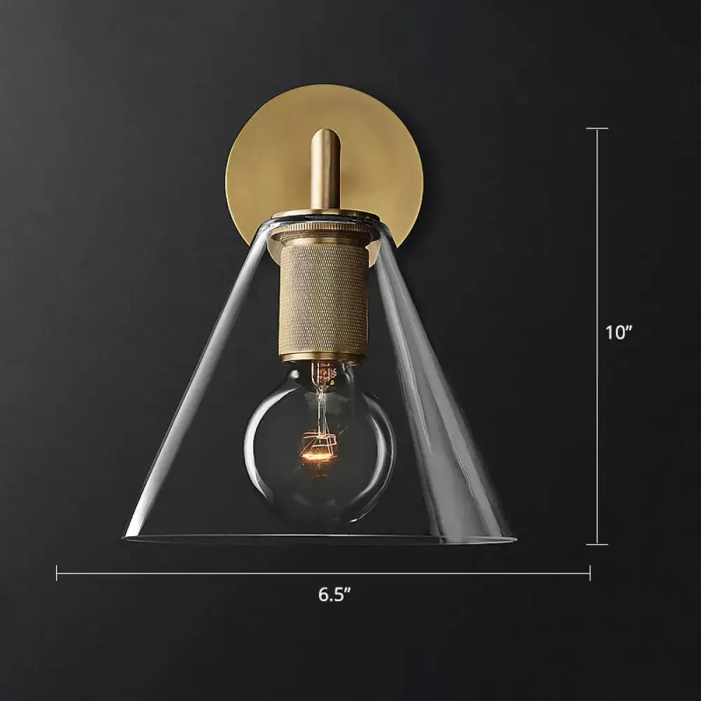 A modern industrial black and brass wall lamp with clear glass conical shade and exposed filament bulb fixture type
