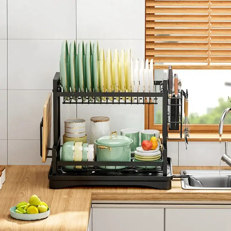 Industrial black and gold two tier metal kitchen storage rack holding green and white plates mugs and a pot