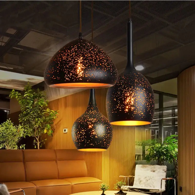 Industrial black and gold etched wrought iron chandelier with speckled black metal pendant lights and warm amber glow
