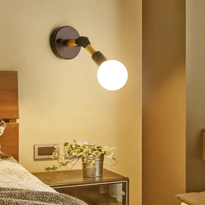Industrial black and ocean blue wall sconce with matte black base, yellow and black arm, and glowing white globe bulb for bedroom use