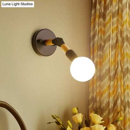 Industrial black and ocean blue wall sconce with matte black base, wood and metal arm, and glowing globe bulb