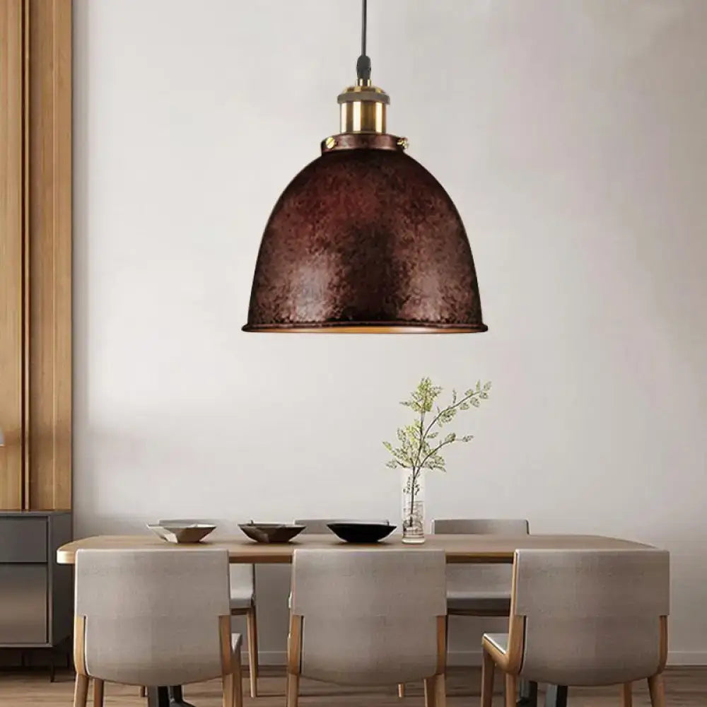 A rustic bronze antique style dome pendant lamp with hammered metal finish and brass hardware above dining table