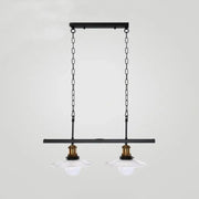 Black metal pendant light fixture with two clear glass shades and brass accents for kitchen island lighting