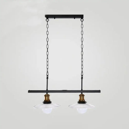 Black metal pendant light fixture with two clear glass shades and brass accents for kitchen island lighting