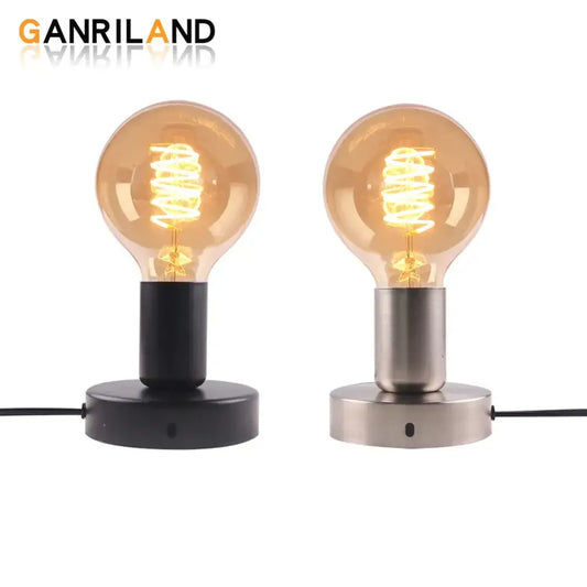 Two vintage industrial desk lamps with amber glass globes featuring spiral filament bulbs on black and bronze lamp bases