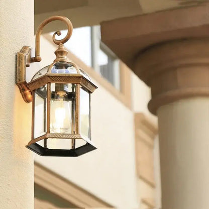 Industrial black bronze wall lamp with antique brass hexagonal lantern and clear glass panels on black bronze wall mount