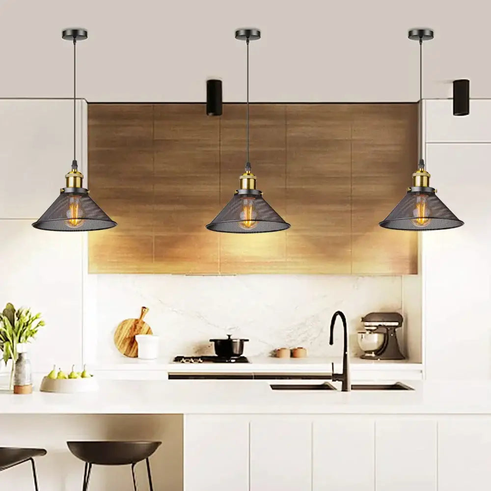 Three industrial pendant lights with dark gray black cage mesh shades and brass hardware above a modern kitchen island decorbites black cage