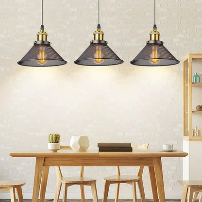Three black cage pendant lights with brass hardware hang above a wooden table in decorbites black cage style