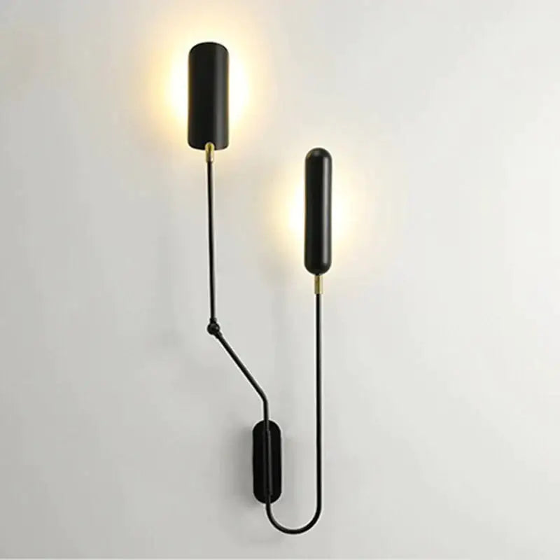 Black cylindrical emma industrial wall lamp with sleek minimalist design and gold-toned accents for bedroom reading light