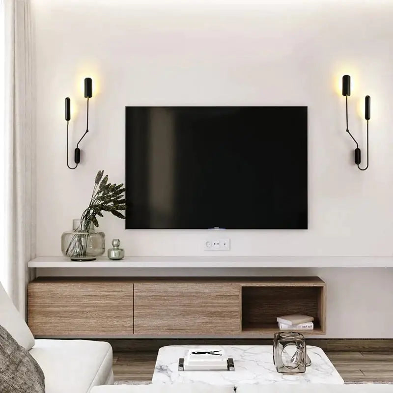 Black flat-screen television mounted on white wall above wooden media console with emma industrial wall lamp bedroom reading light