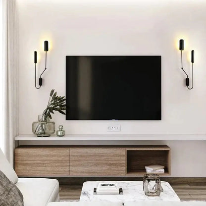 Black flat-screen television mounted on white wall above wooden media console with emma industrial wall lamp bedroom reading light