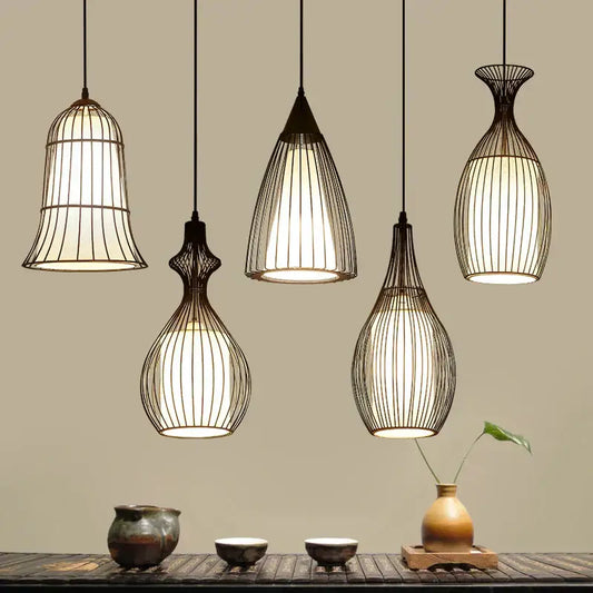 Five black iron cage pendant lights with warm glowing interiors hang above a wooden table in dining room decorbites iron cage style