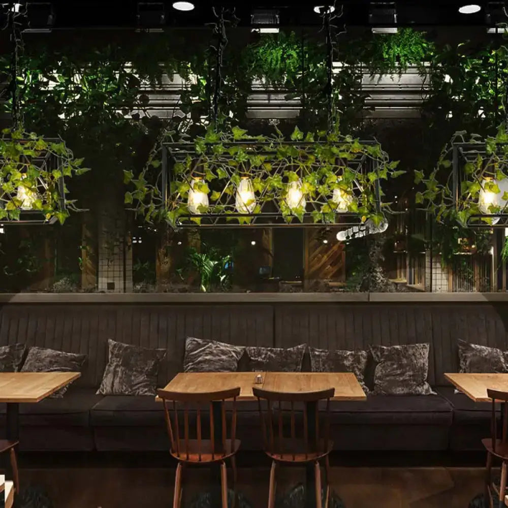 Black velvet cushions with subtle sheen arranged on dark wood bench under industrial black metal cuboid plant island lamp light fixture