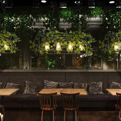 Black velvet cushions with subtle sheen arranged on dark wood bench under industrial black metal cuboid plant island lamp light fixture