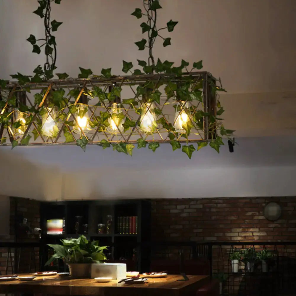 Industrial black metal cuboid plant island light fixture with green ivy and exposed filament bulbs for dining room