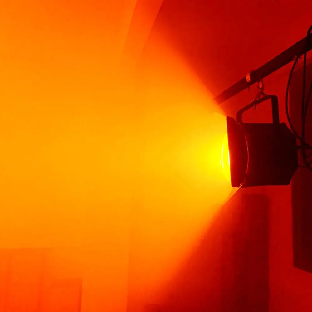 Industrial black metal stage lighting with barn doors emitting a warm orange stage lighting effect