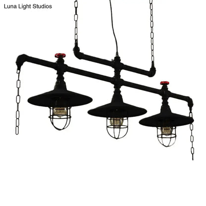 Industrial black pipe chandelier with three hanging lanterns featuring red valve caps and protective wire cages for dining room lighting