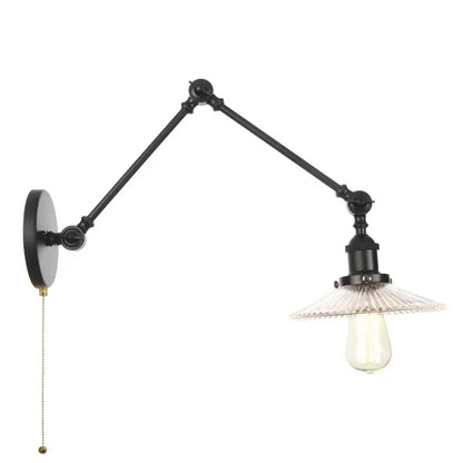 Industrial black swing arm wall light fixture with articulated arms and clear faceted glass shade over exposed bulb