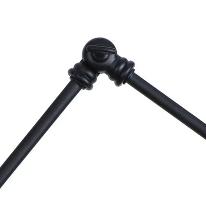 Black metal tripod joint with matte finish and ornate design on industrial black swing arm wall light fixture