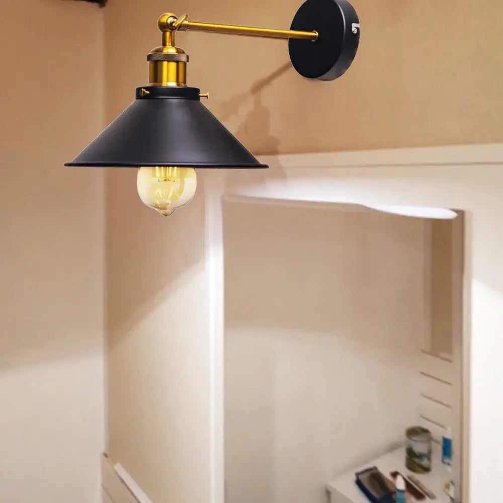 Black metal wall lamps with brass-finished arm and base featuring conical shade and exposed edison led bulb for bedroom lighting