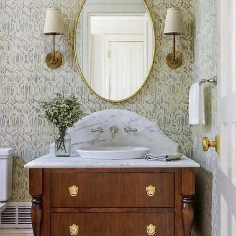 Industrial brass wall lamps set of 2 with linen shades beside a classic wooden vanity with white marble countertop and gold lion-head pulls