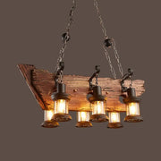 Rustic wooden beam lantern island pendant light fixture with three clear glass lanterns and black metal chains by DecorBites