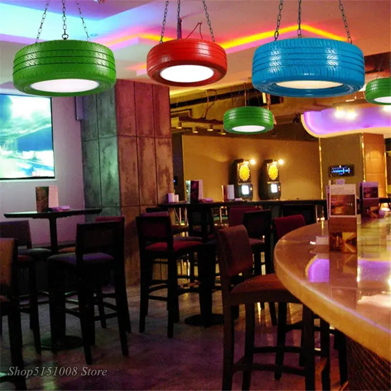 Colorful green red and blue DecorBites industrial rubber tire pendant lights hang above a bar for kitchen décor