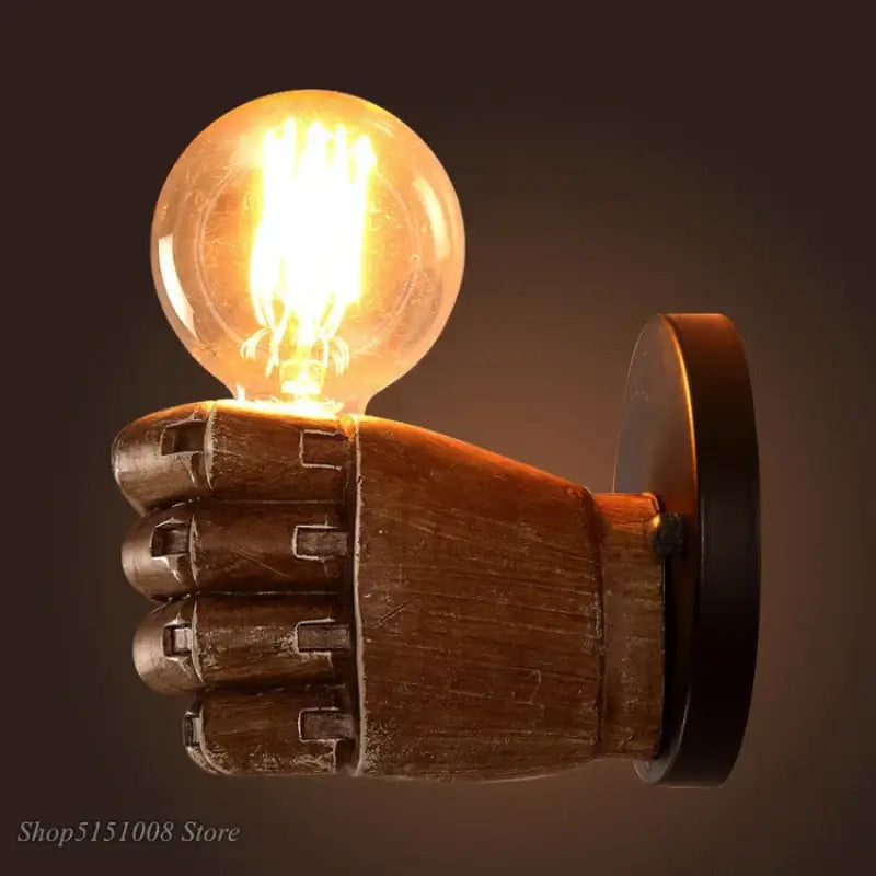 A rustic wooden hand-shaped industrial fist resin wall lamp with a glowing filament bulb for vintage bedroom decorbites decor