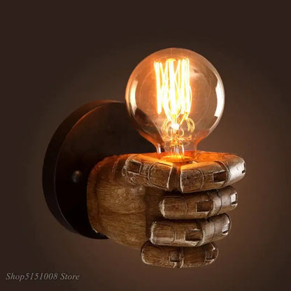 A rustic wooden industrial fist resin wall lamp hand sconce holding a glowing filament bulb for vintage decorbites