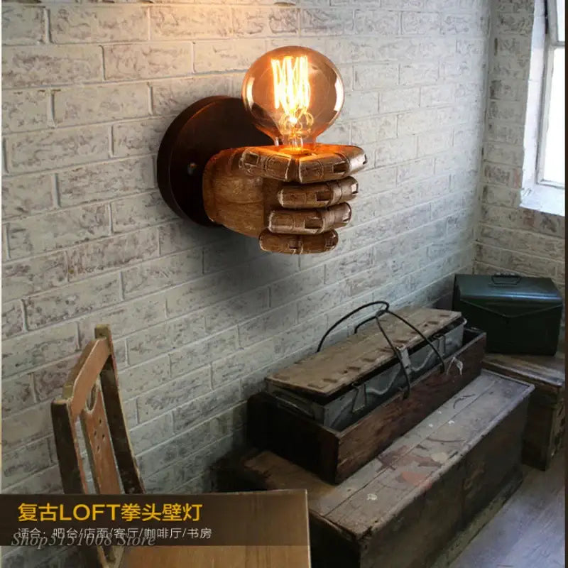 A rustic wooden industrial fist resin wall lamp hand sconce holding a glowing filament bulb for bedroom decorbites