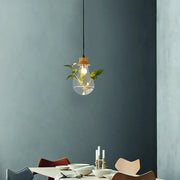 Industrial glass and wood pendant light kit with exposed bulb and green plant stems for dining room illumination