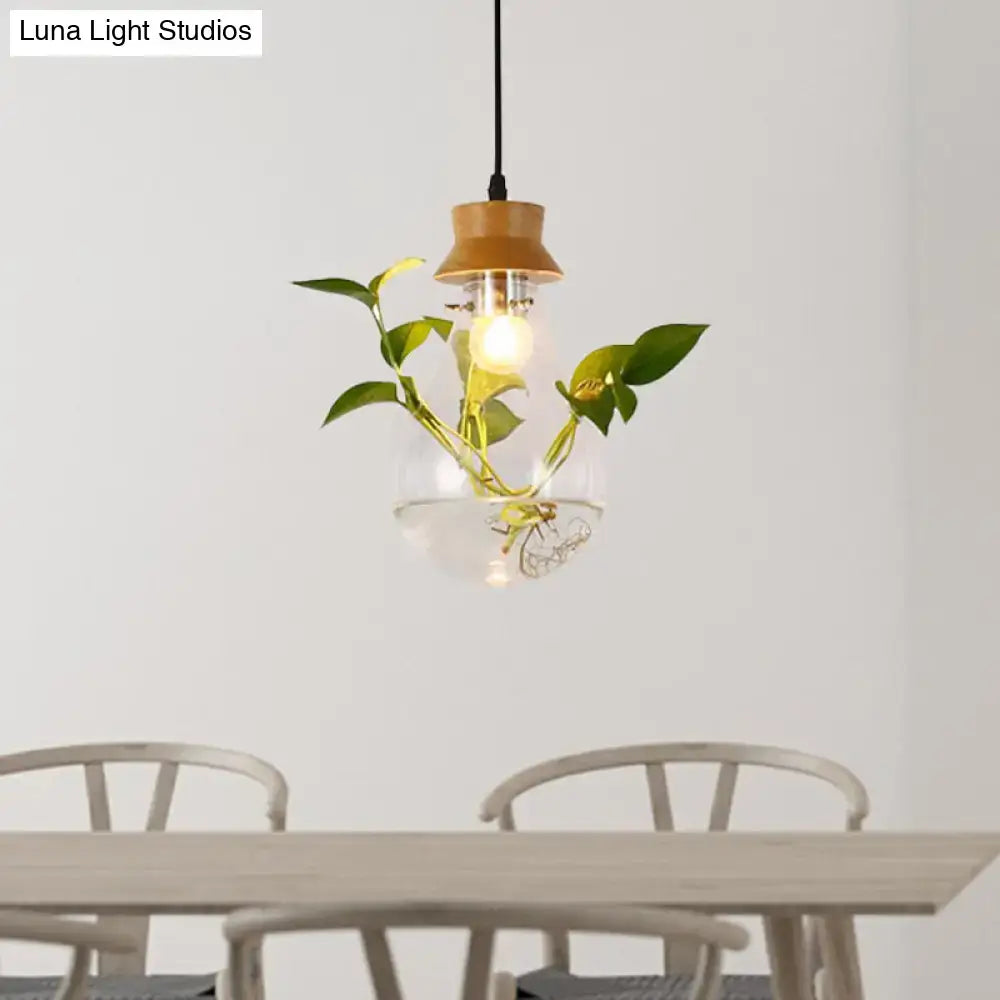 Industrial glass and wood pendant light kit with exposed bulb and green vines inside globe for dining room use