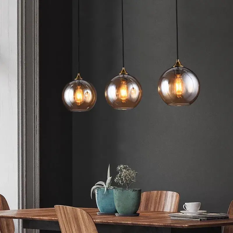 Three hanging spherical glass pendant lights with brass accents and warm filament bulbs for kitchen decorbites industrial glass pendant