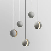 Industrial gray and gold decorbites cement pendant light with sphere shape and gold-accented cutouts for dining room decor