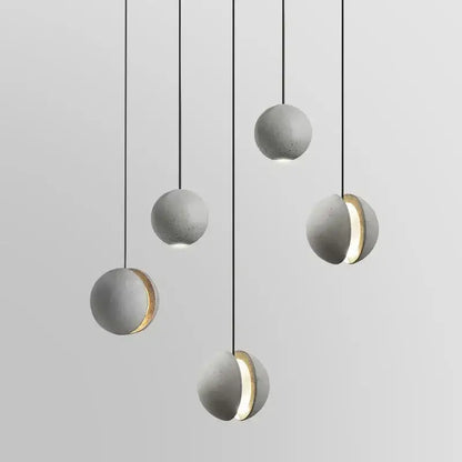 Industrial gray and gold decorbites cement pendant light with sphere shape and gold-accented cutouts for dining room decor