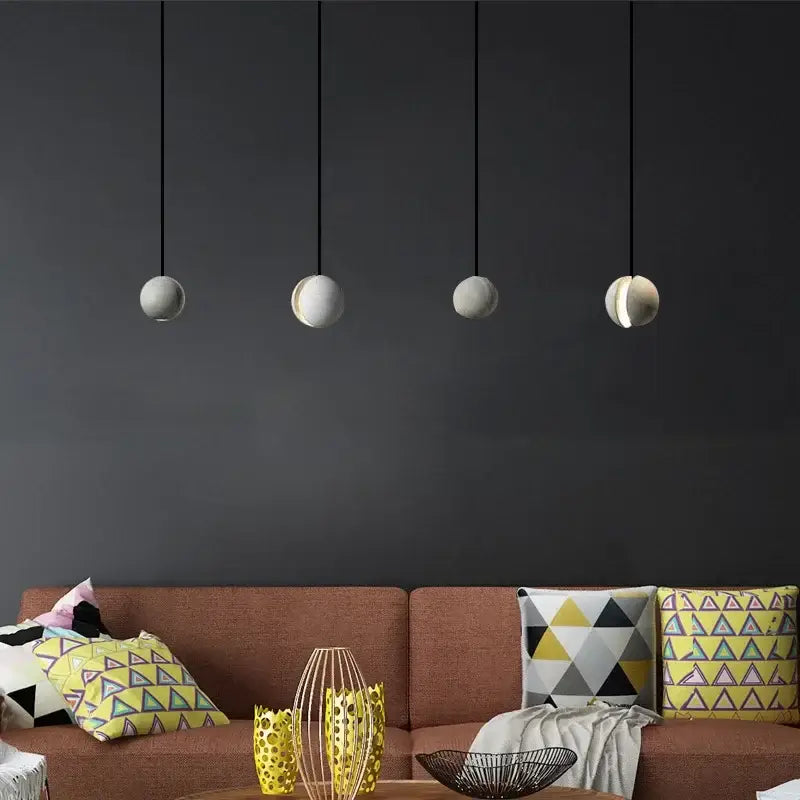 Industrial gray and gold decorbites cement pendant light with four matte white ceramic spherical shades hanging on black cords