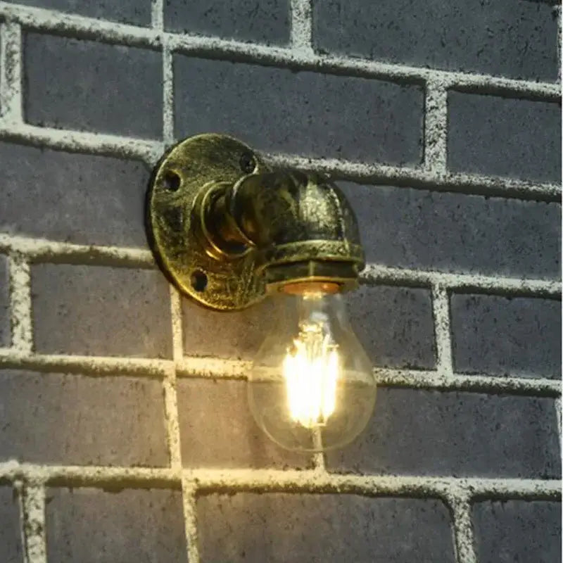Industrial iron pipe wall sconce with brass finish and glowing filament bulb ideal for bedroom decorbites industrial iron style