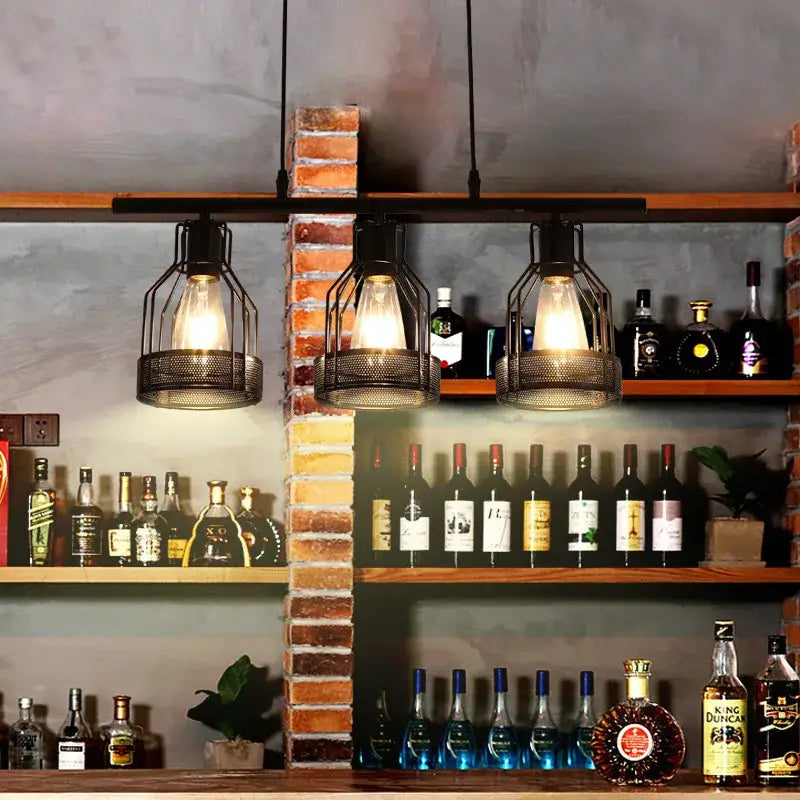 Three black metal mesh cage pendant lights with exposed bulbs hang above a bar shelf decorbites industrial loft chandelier