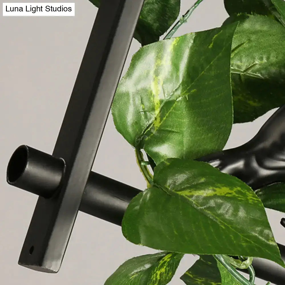 Black metal industrial metal plant stand with green artificial leaves complementing DecorBites™ pendant light