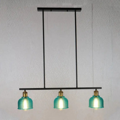 Modern black metal chandelier with three teal glass shades and brass accents for island lighting with red yellow blue bowls
