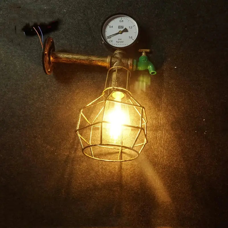 Industrial retro wall light featuring a brass-finished cage bulb, green faucet, and pressure gauge pipe fixture