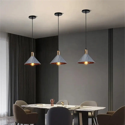 Three industrial retro pendant lamps with textured gray shades and brass accents hang above a dining table decorbites industrial retro