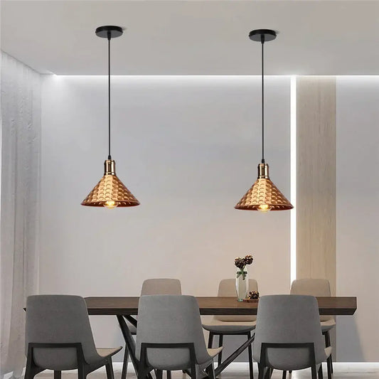 Two copper hammered finish industrial retro pendant lamps with black cords hang above a dining table decorbites industrial retro